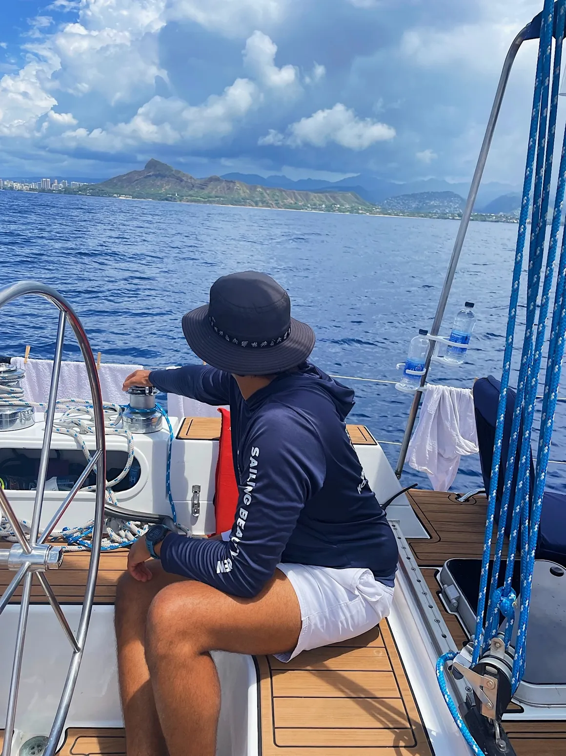 Captain seated in the cockpit of Sailing Beauty with Diamond Head in the background.