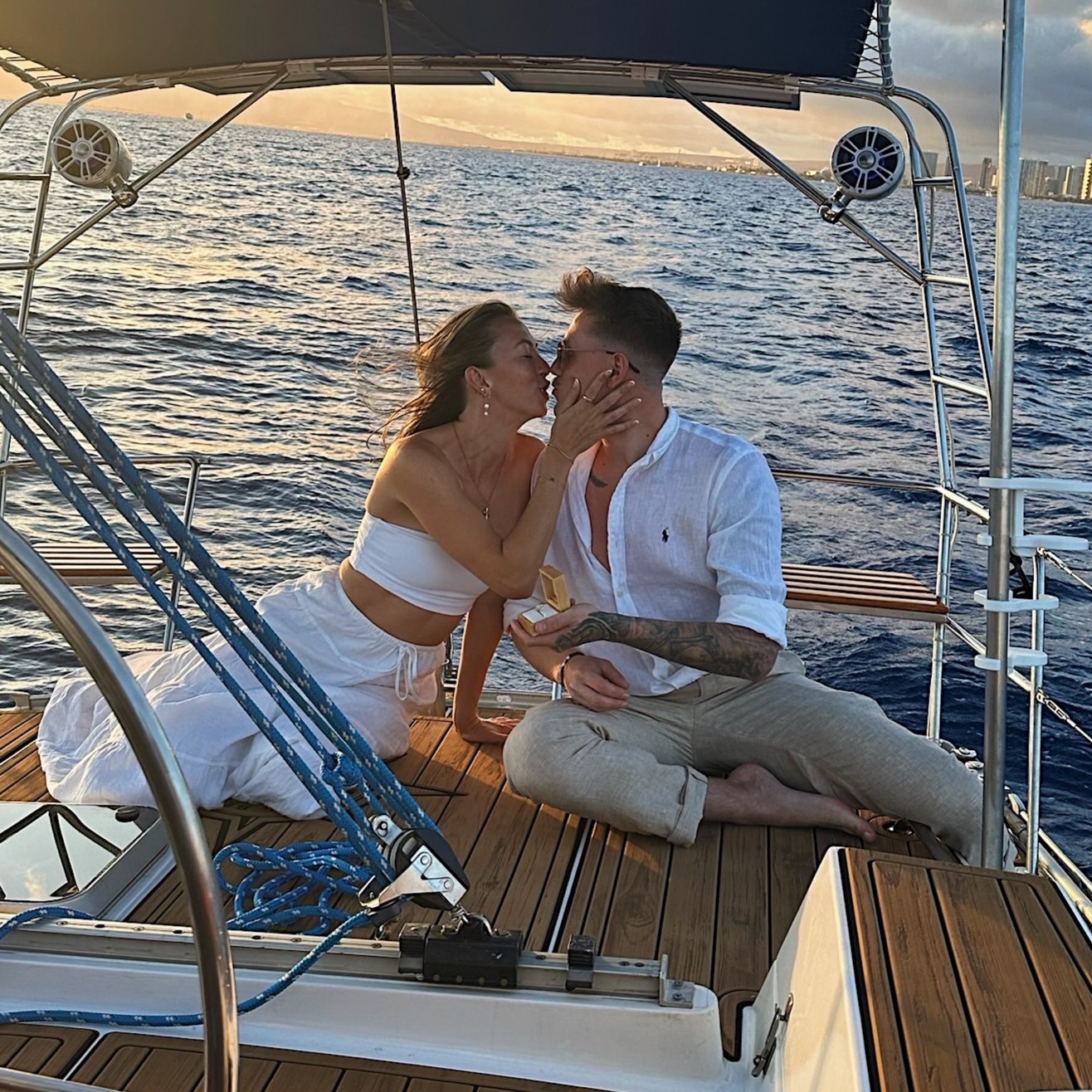 Couple celebrating a proposal on Sailing Beauty with Honolulu skyline behind them.