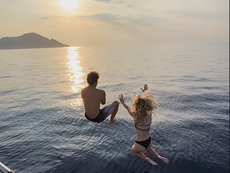 Two guests jumping off stern