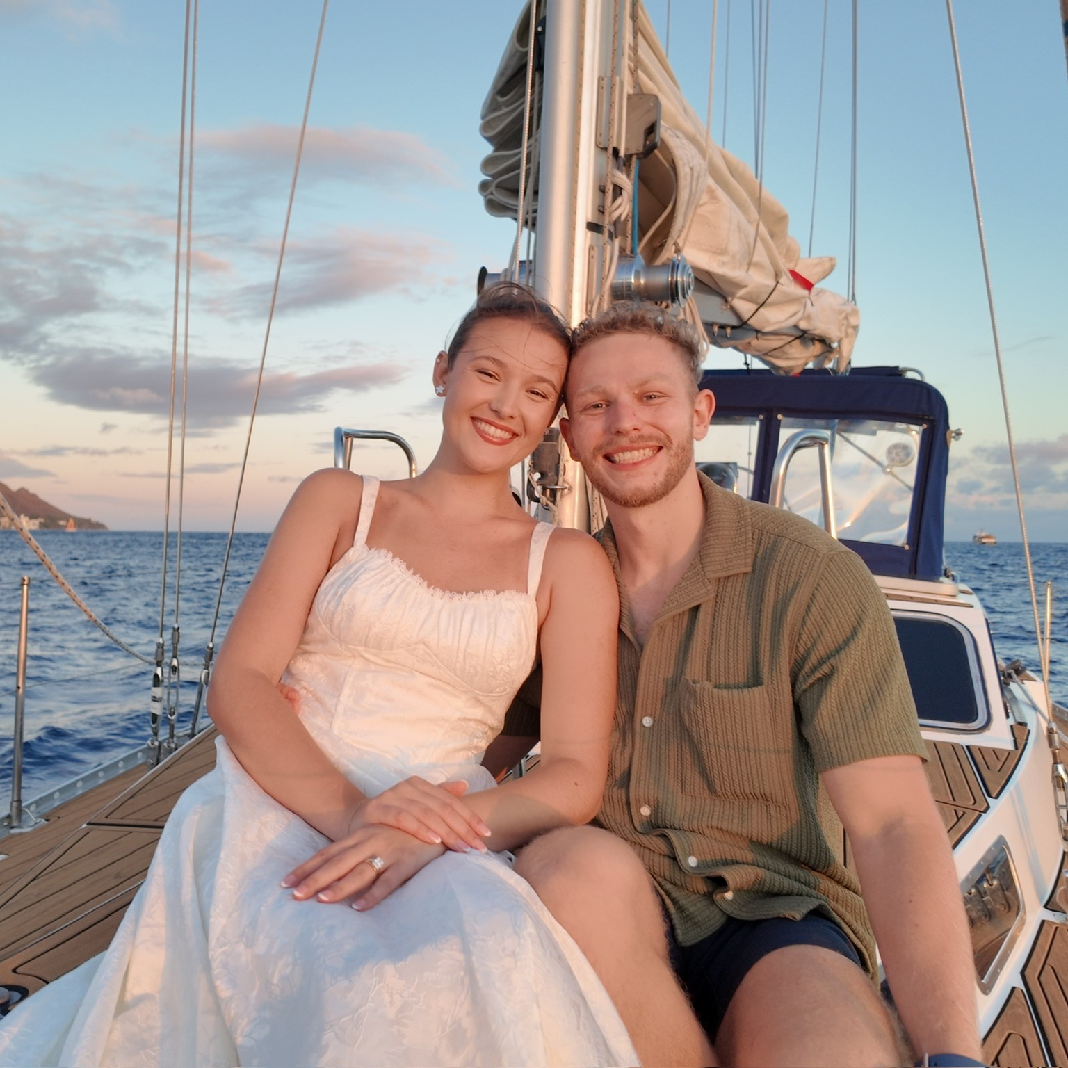 Newly married couple seated together on the bow of Sailing Beauty at sunset.